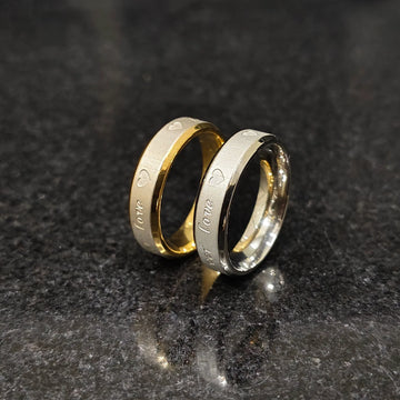 Lamha 2 forever love rings for men with heart and love engravings in gold and silver tones on black stone background