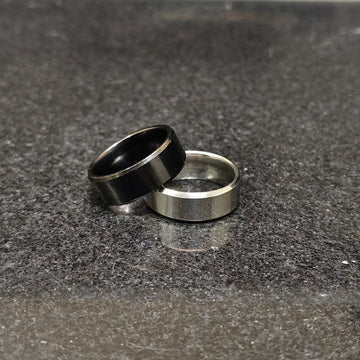 2 rings black and silver for men in pakistan with simple modern design on dark textured surface