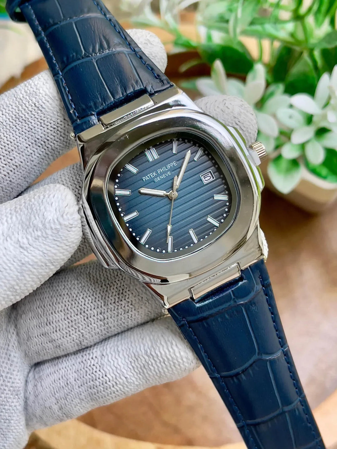 Patek Philippe Watch with blue leather strap and silver case held by gloved hand