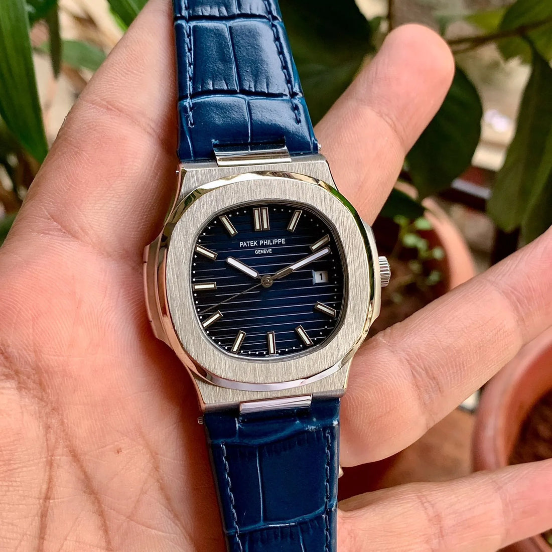 Patek Philippe Watch with blue leather strap and silver case held by gloved hand
