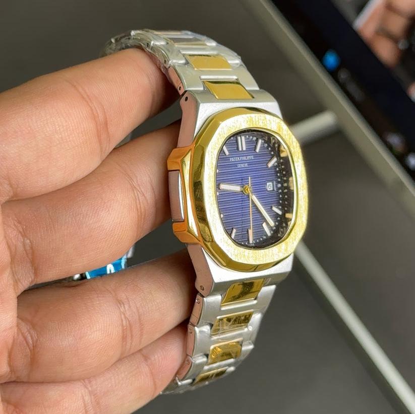 Patek philippe watch in two tone blue color with gold and silver bracelet held by gloved hand