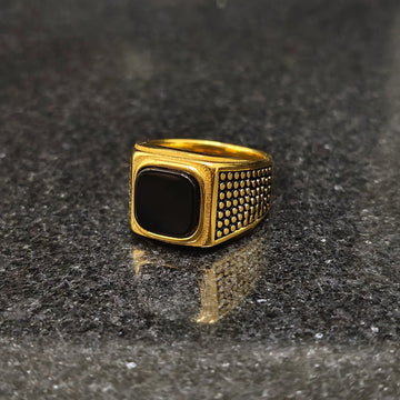 Lamha retro golden ring for men in best design with black stone and textured sides on dark surface