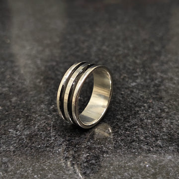 Silver black line ring for men in best design with a polished finish on a dark granite surface