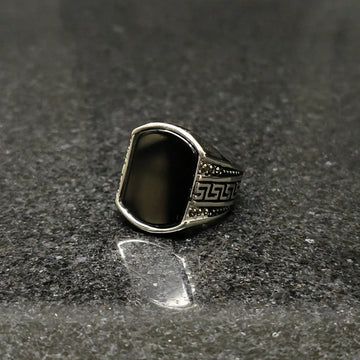 Silver Medusa stone rinf or men with black stone and intricate side carvings on dark surface