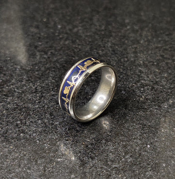 Lamha steal silver ring for men with blue and gold intricate designs on a dark stone surface