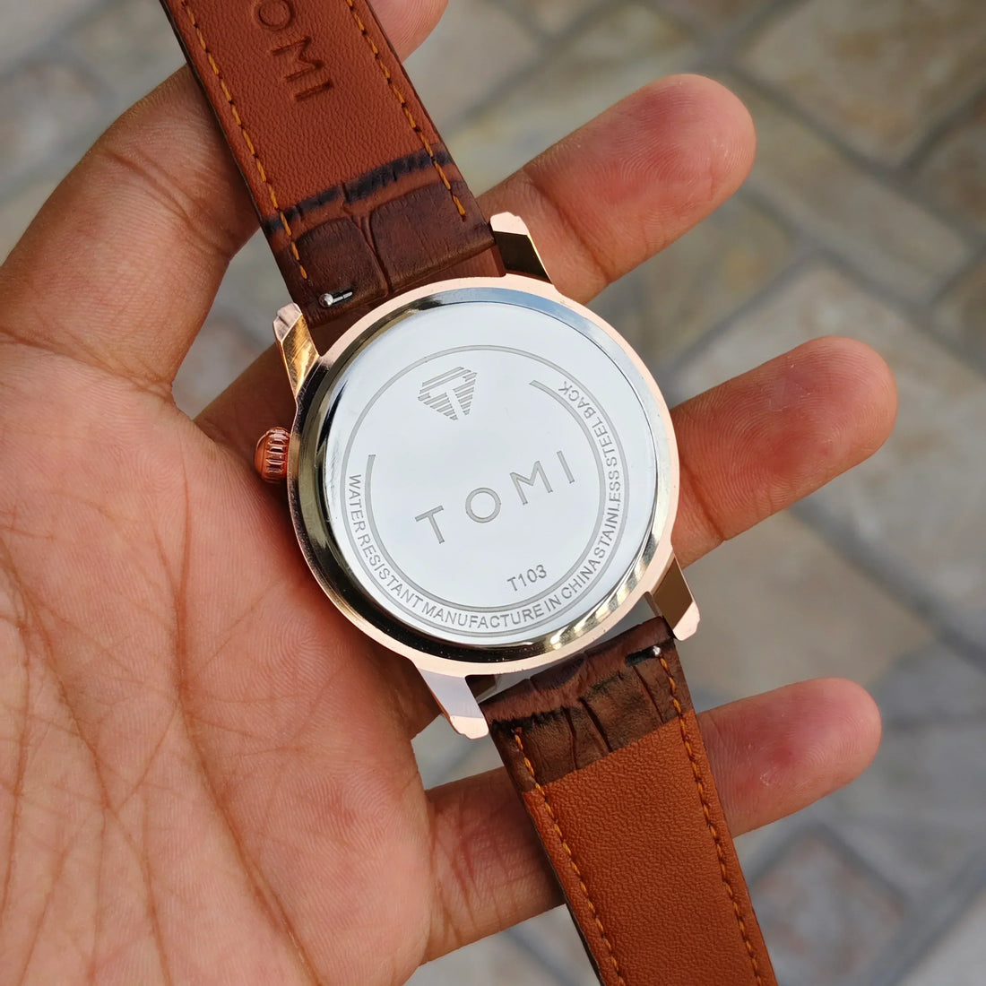 tomi t 103 dual strap watch for men with brown leather strap and white round dial held in hand
