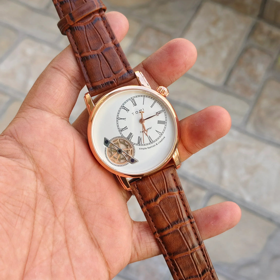 tomi t 103 dual strap watch for men with brown leather strap and white round dial held in hand