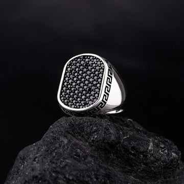 Silver Versace Ring For Men with black stones and Greek key design on band displayed on black rock