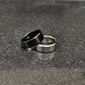 2 rings black and silver for men in pakistan with simple modern design on dark textured surface