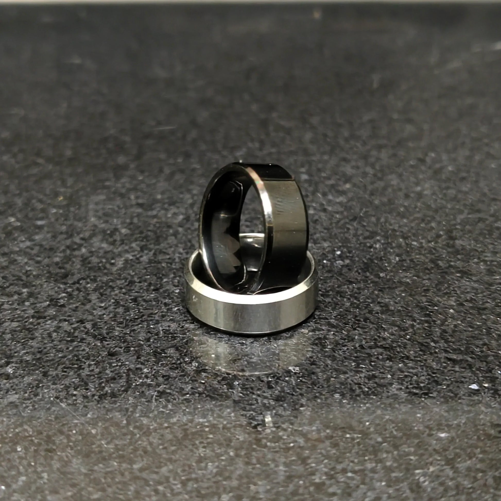 2 rings black and silver for men in pakistan displayed on a dark textured surface by Lamha