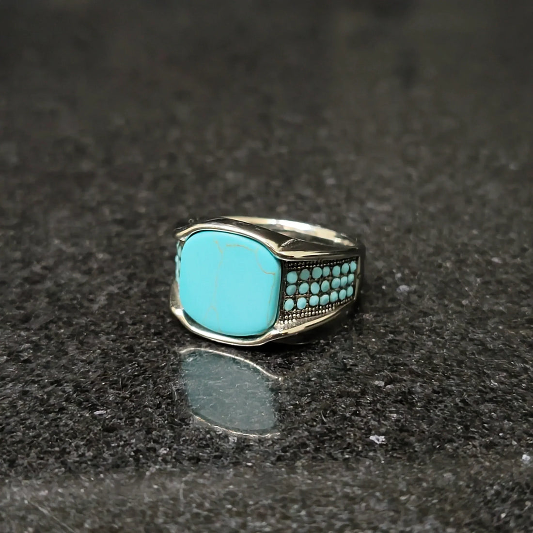 Blue feroza ring for men with silver band and turquoise stones by Lamha on black surface
