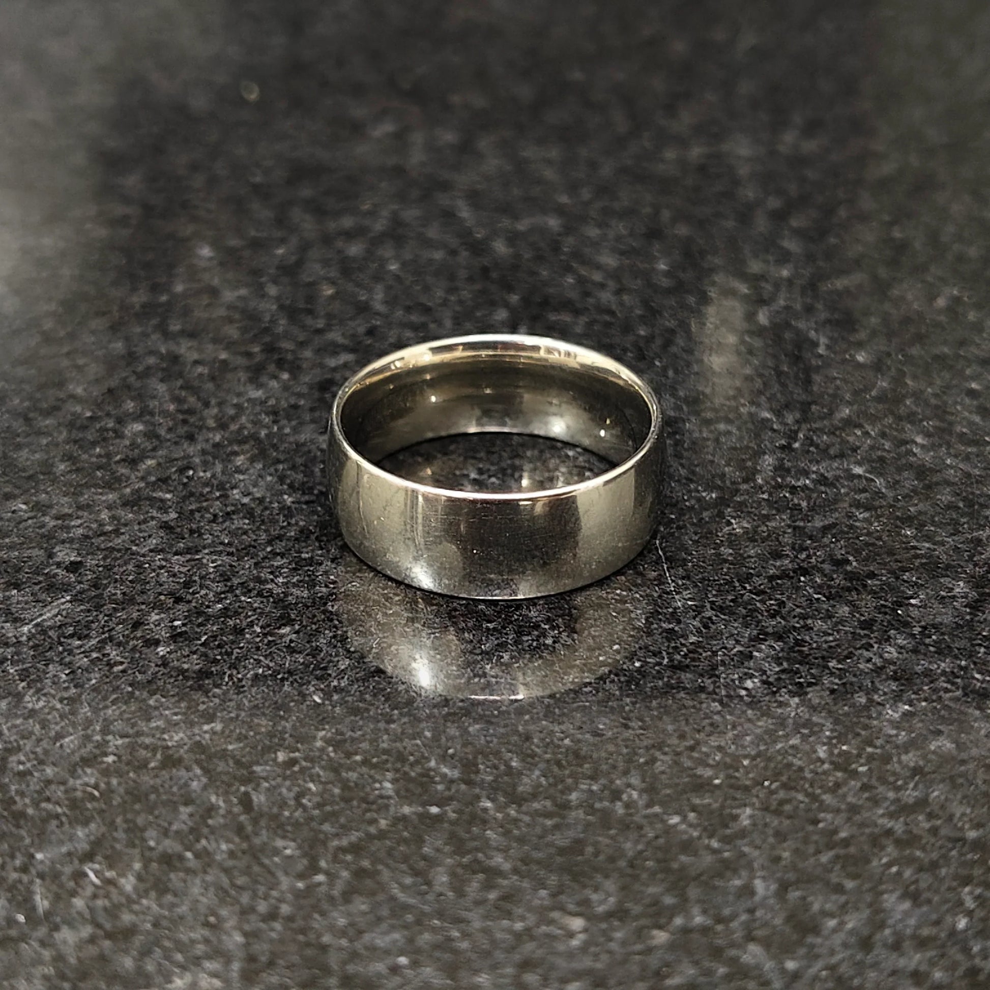 Classic silver ring for men with smooth polished finish by Lamha on black textured surface
