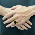 Golden Swiss medusa ring for men worn on finger with black center and intricate gold design