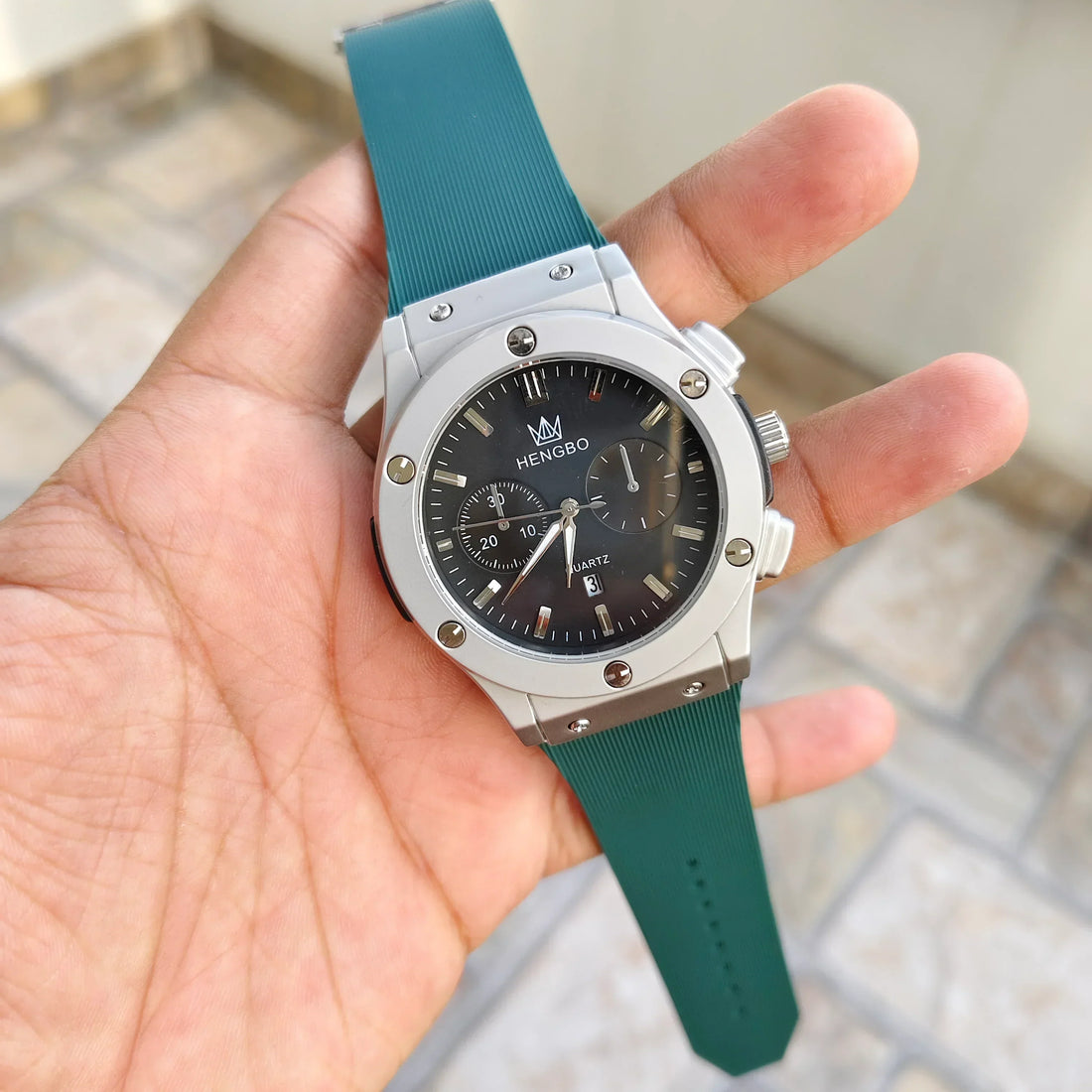 Hublot Green Strap Watch with silver case and black dial held in hand by Lamha