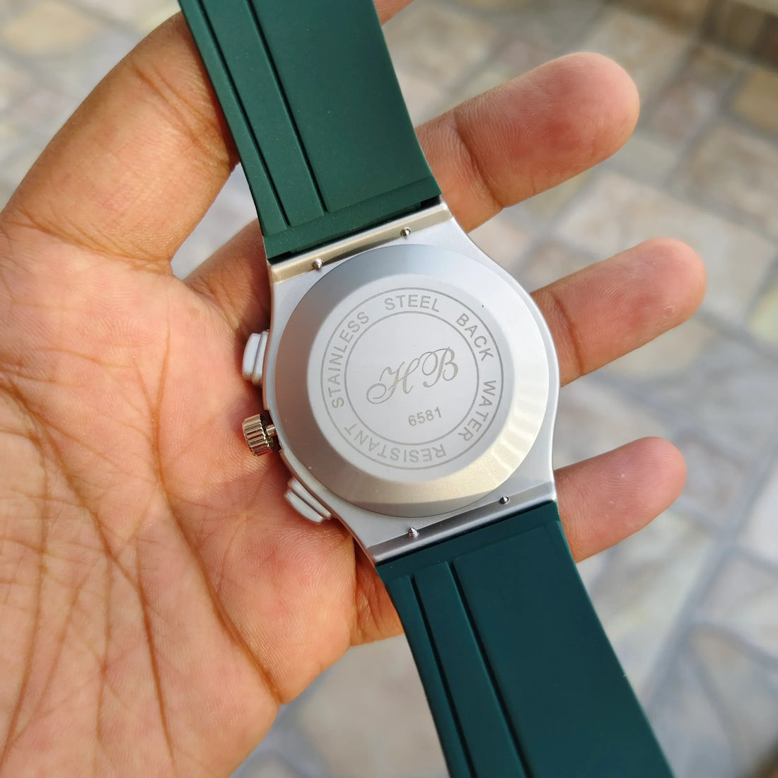 Hublot Green Strap Watch with silver case and black dial held in hand by Lamha