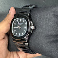 Patek Philippe In Black wristwatch with black metal band and sleek round dial held in hand
