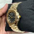 Patek philippe watch in golden black with a sleek gold bracelet and black dial held in hand