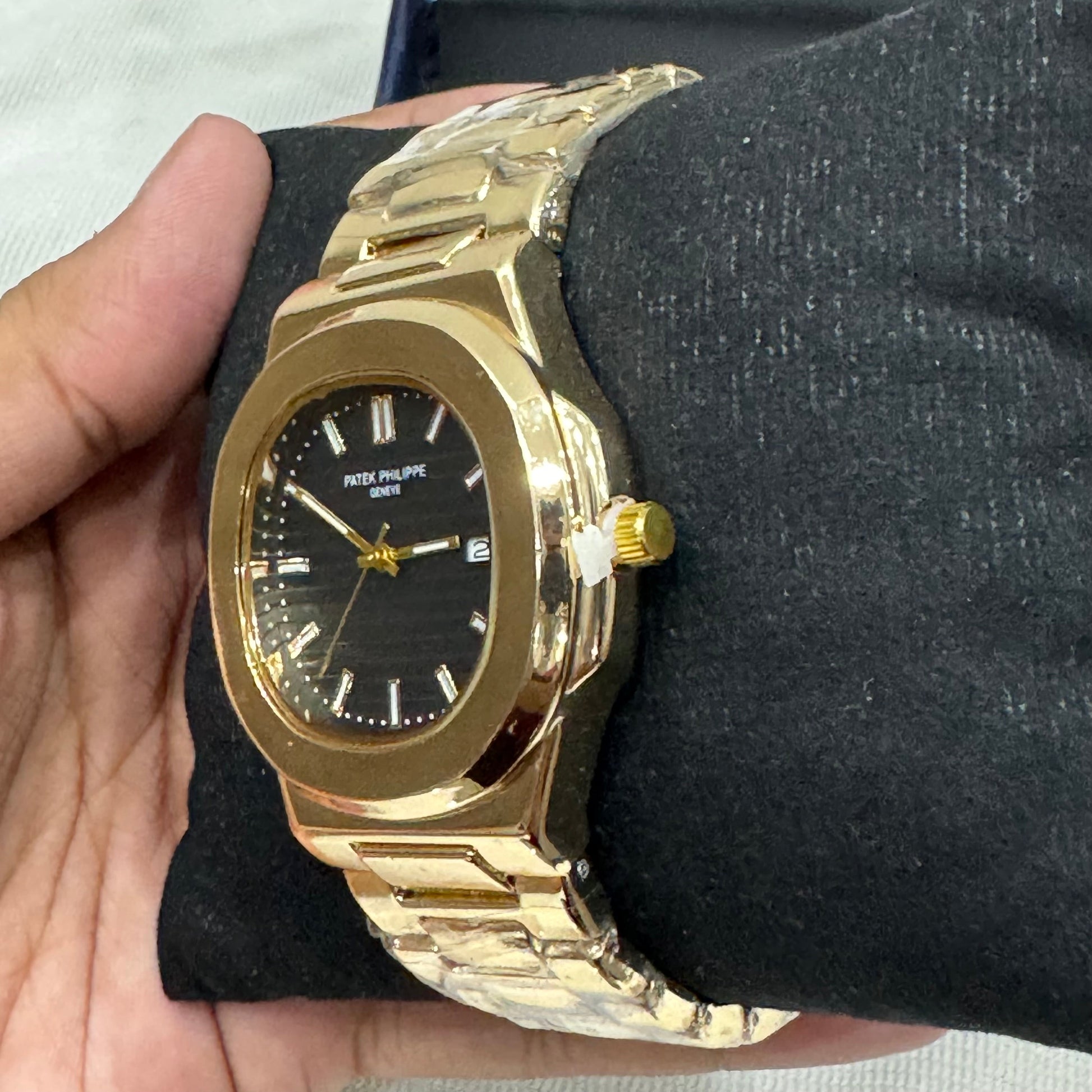Patek philippe watch in golden black with a sleek gold bracelet and black dial held in hand