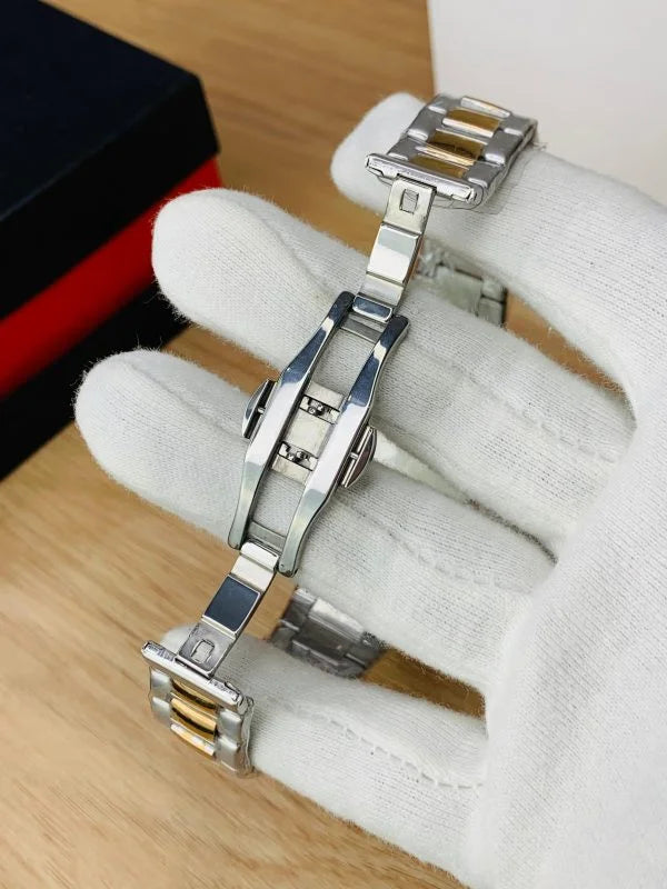 Close-up of silver and gold metal watch bracelet clasp held by gloved hand for patek philippe watch in silver blue