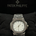 Patek philippe watch in silver white with metal bracelet and date display on black cushion