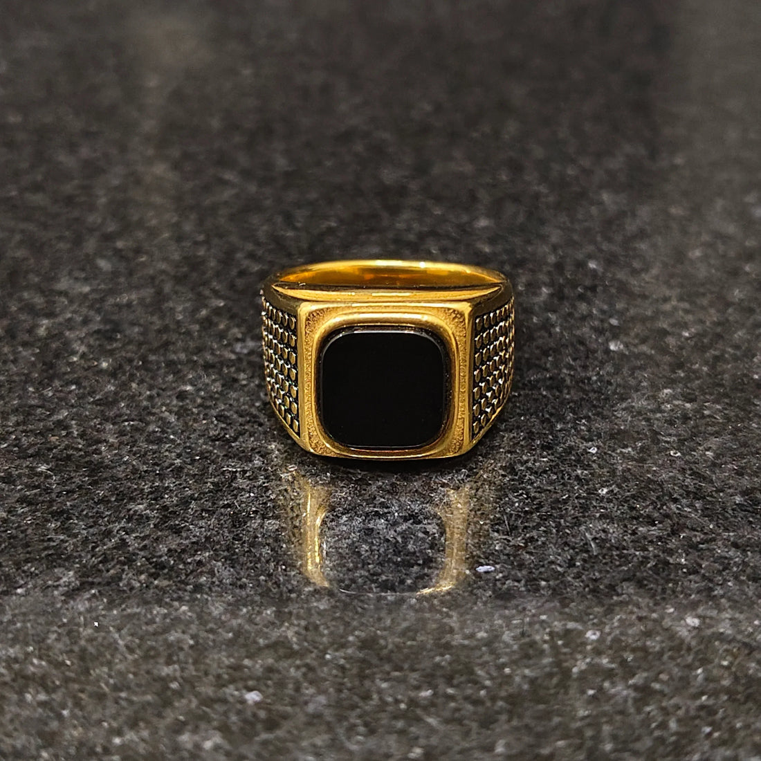 Lamha retro golden ring for men in best design with black stone and textured sides on dark surface