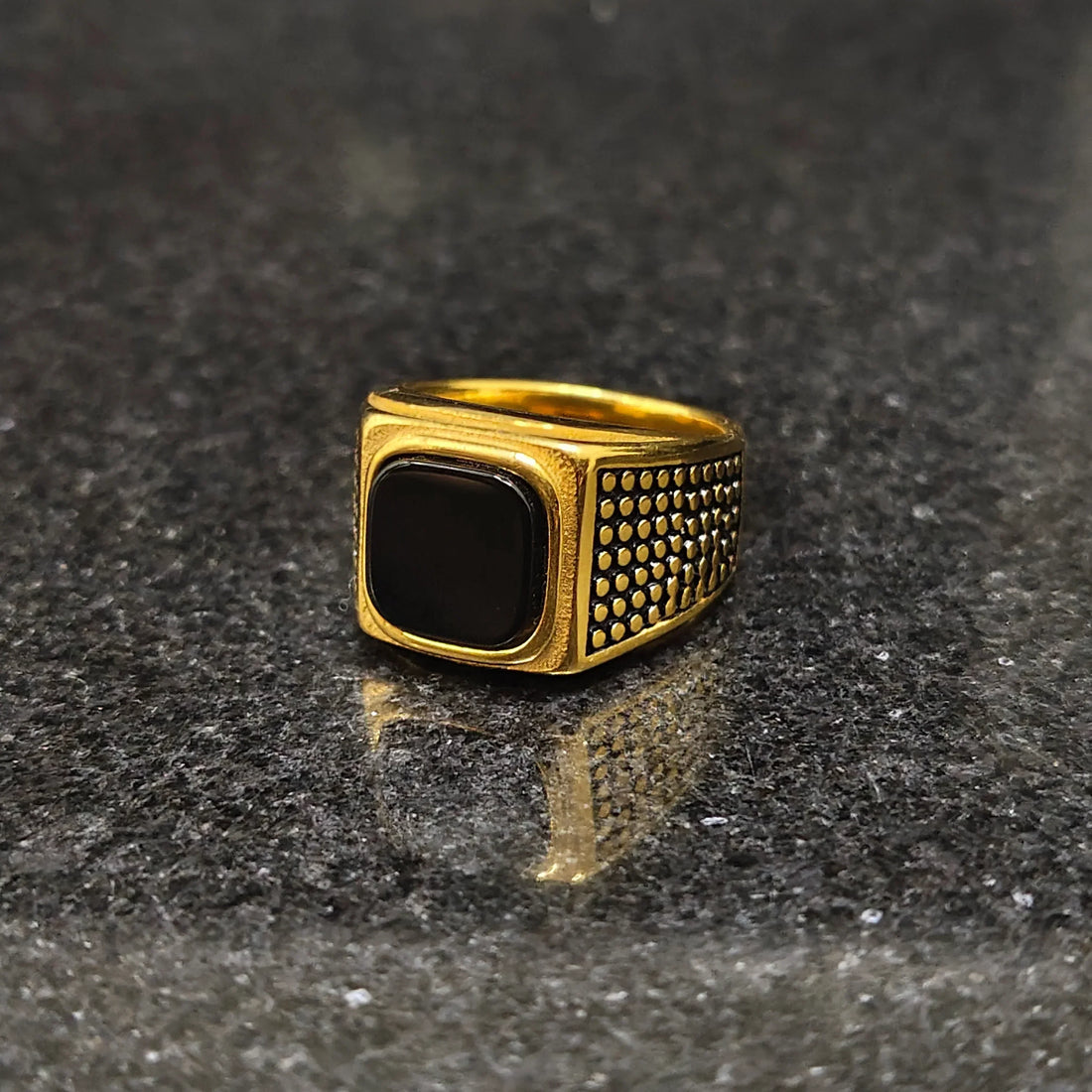 Lamha retro golden ring for men in best design with black stone and textured sides on dark surface