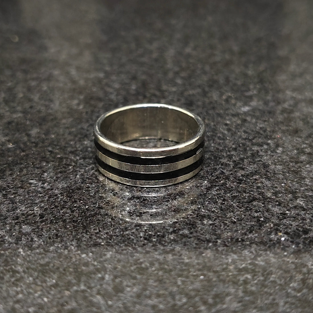 Silver black line ring for men in best design with a polished finish on a dark granite surface