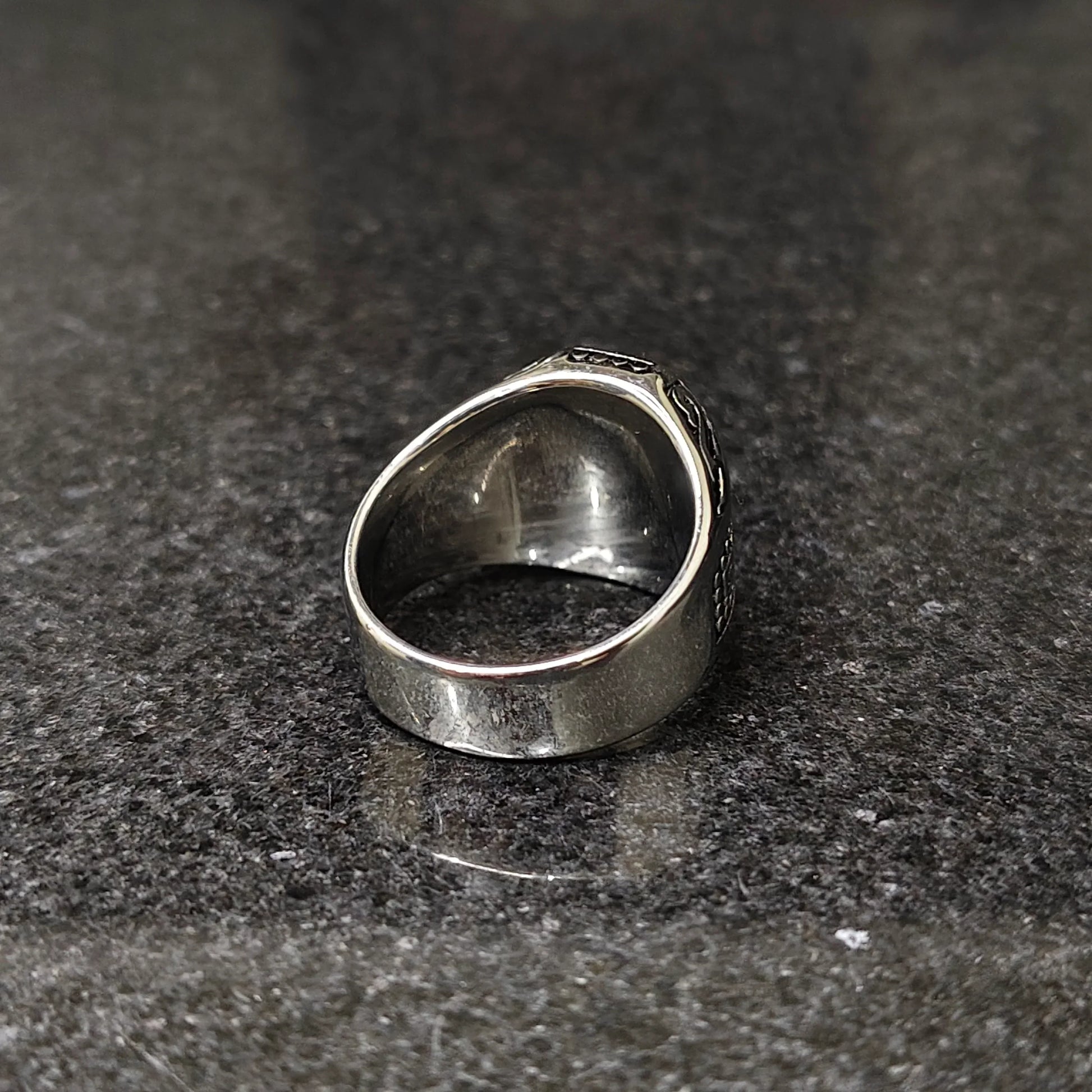 Close-up of silver medusa ring for men on dark textured surface showcasing detailed craftsmanship