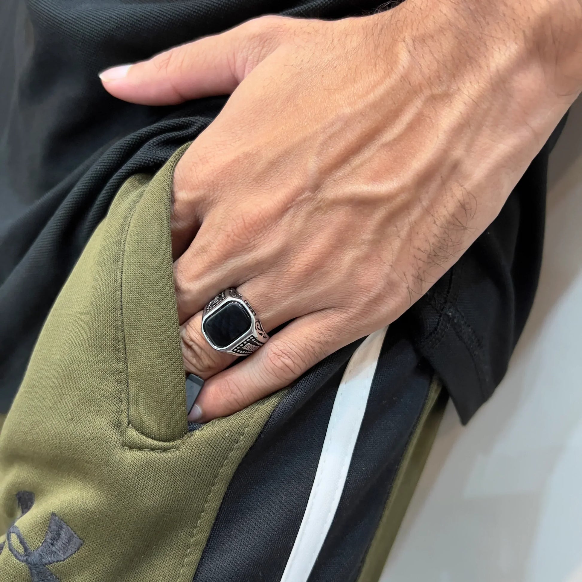 silver medusa ring for men on hand wearing black and green pants with black shirt