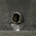 Silver Medusa stone rinf or men with black stone and intricate side carvings on dark surface
