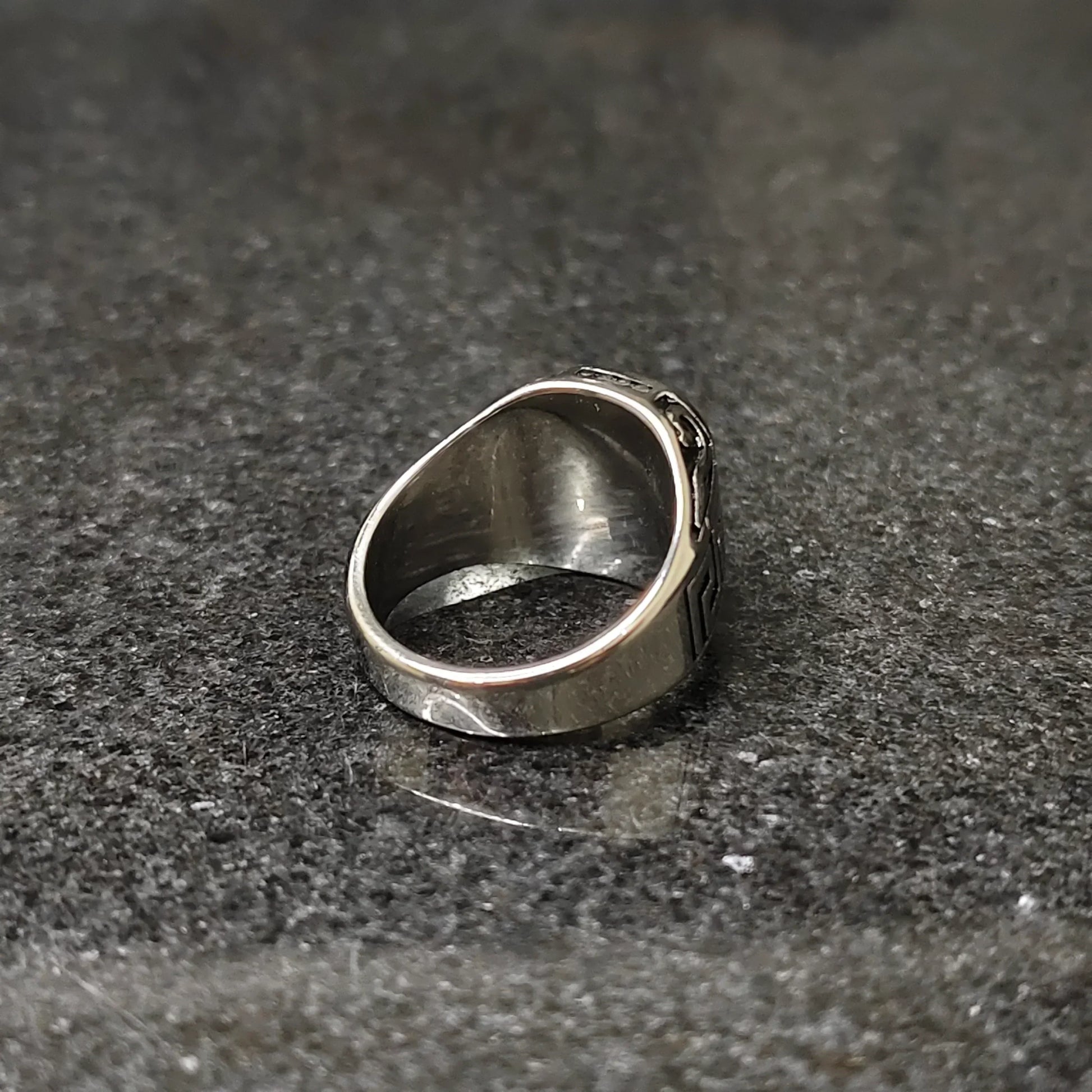 Silver onyx emperor ring for men displayed on black granite surface showcasing smooth inner band and polished silver finish