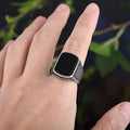 Silver retro ring for men with black square detail worn on finger in outdoor setting