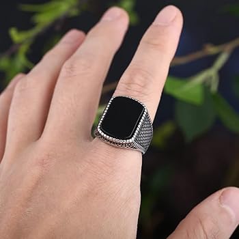Silver retro ring for men with black square detail worn on finger in outdoor setting
