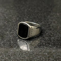 Silver versace medusa ring for men with black rectangular stone and intricate side design on dark surface