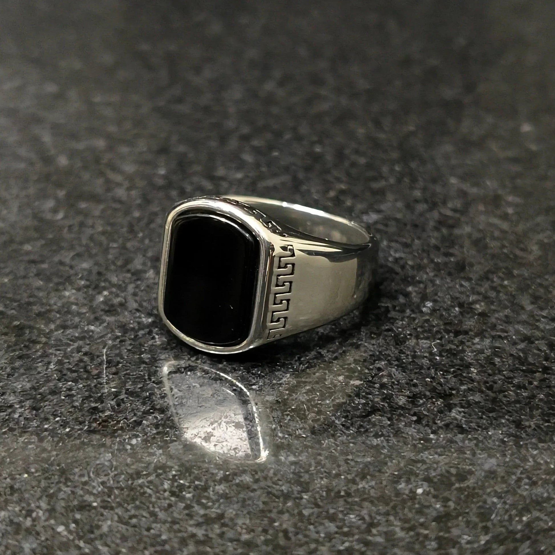 Silver versace medusa ring for men with black rectangular stone and intricate side design on dark surface