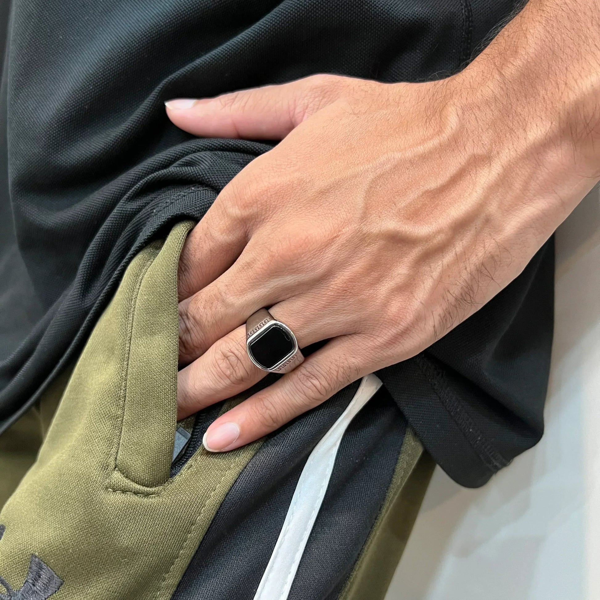 Hand wearing silver versace medusa ring for men with black center on casual outfit