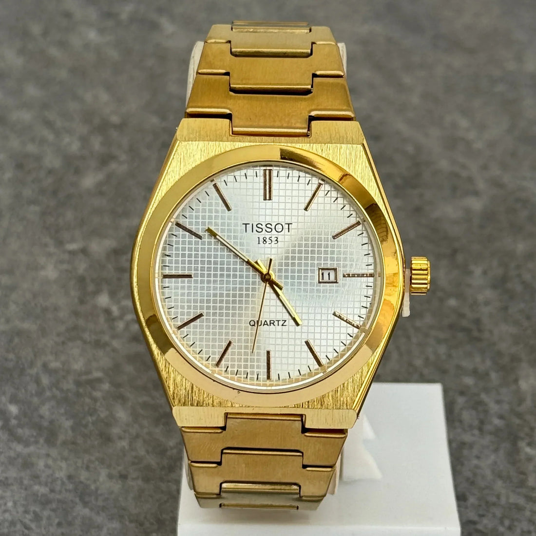 Tissot prx chain watch in gold with white textured dial and date display on a gold metal bracelet