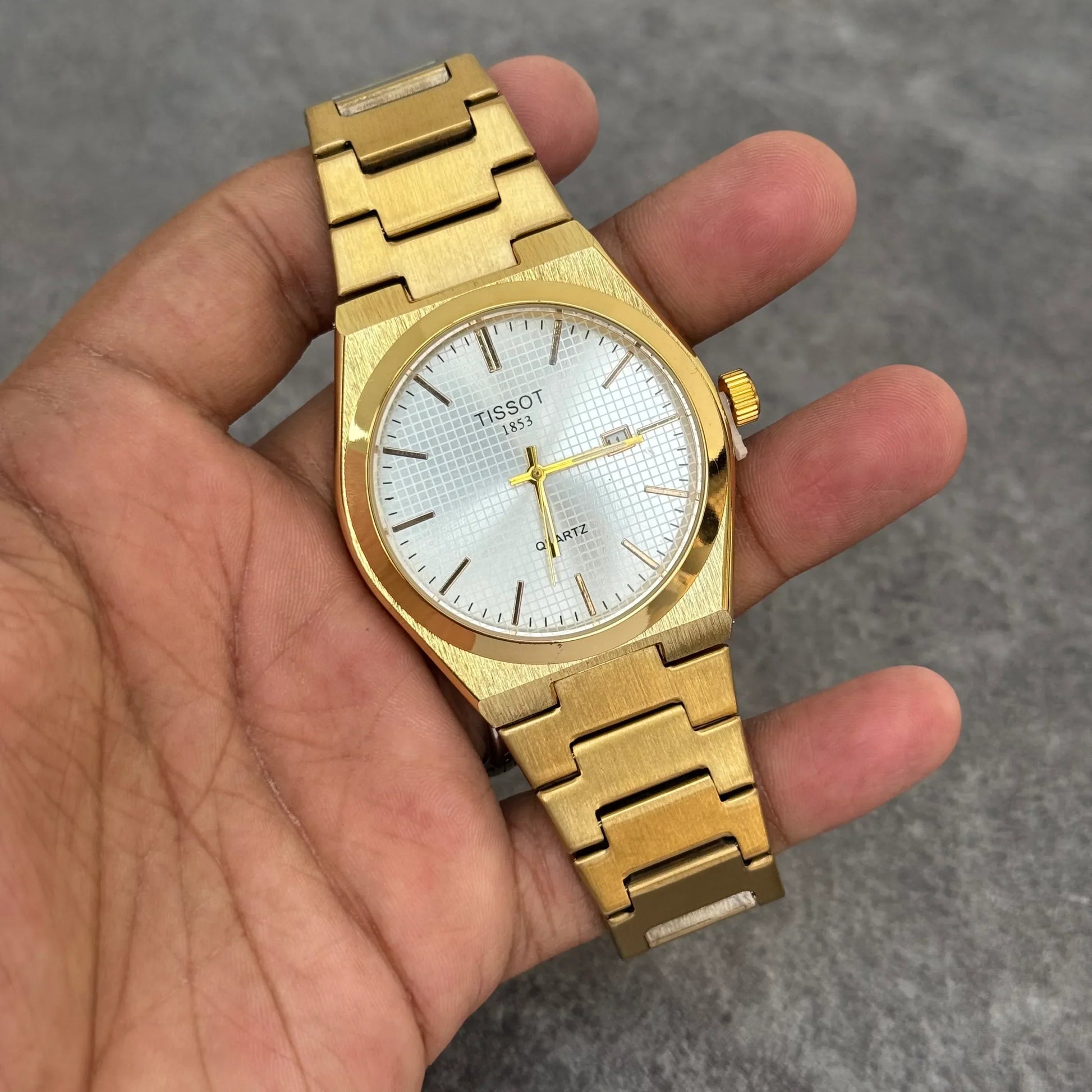 Tissot prx chain watch in gold held in hand featuring white dial and date display