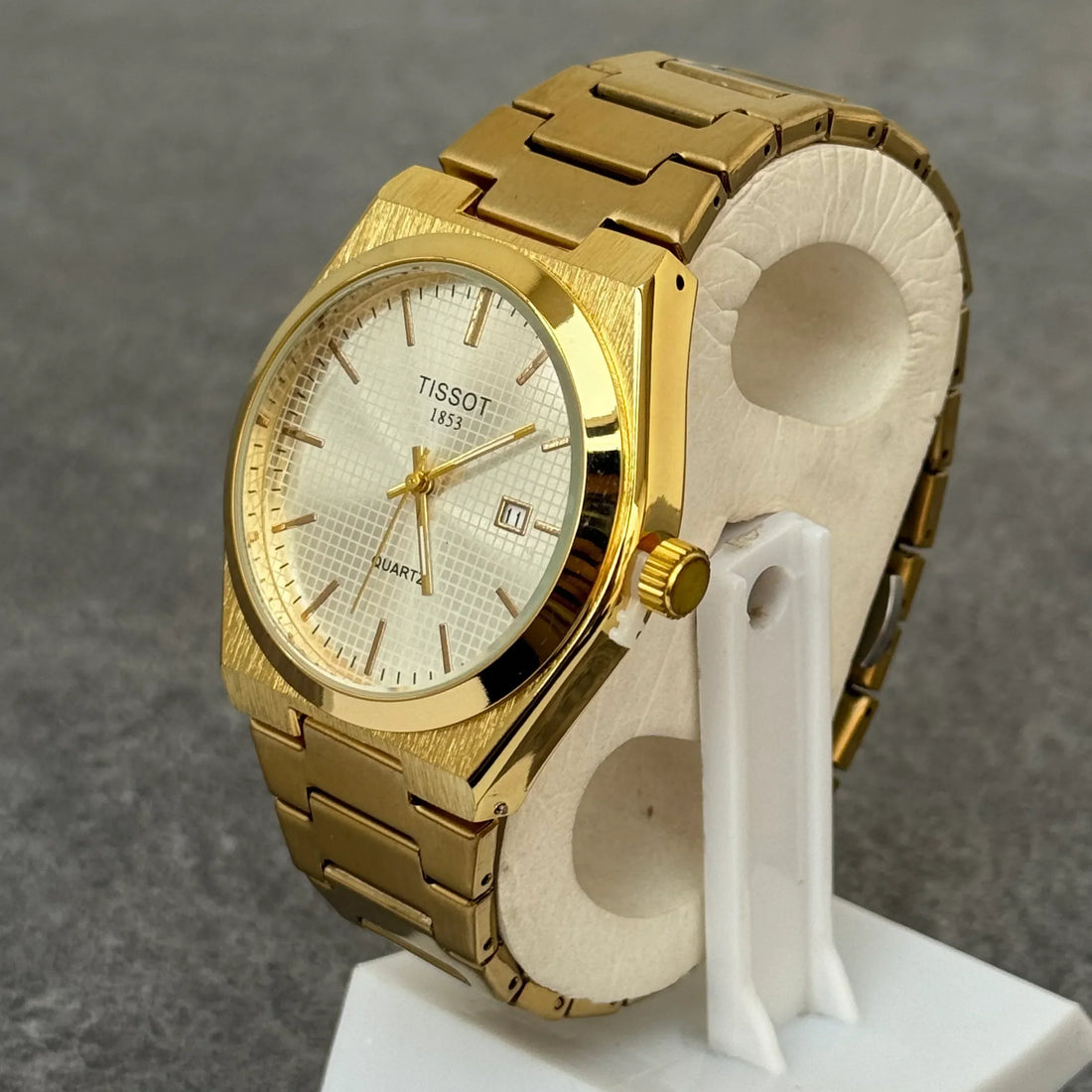 Tissot prx chain watch in gold with white textured dial and date display on a gold metal bracelet