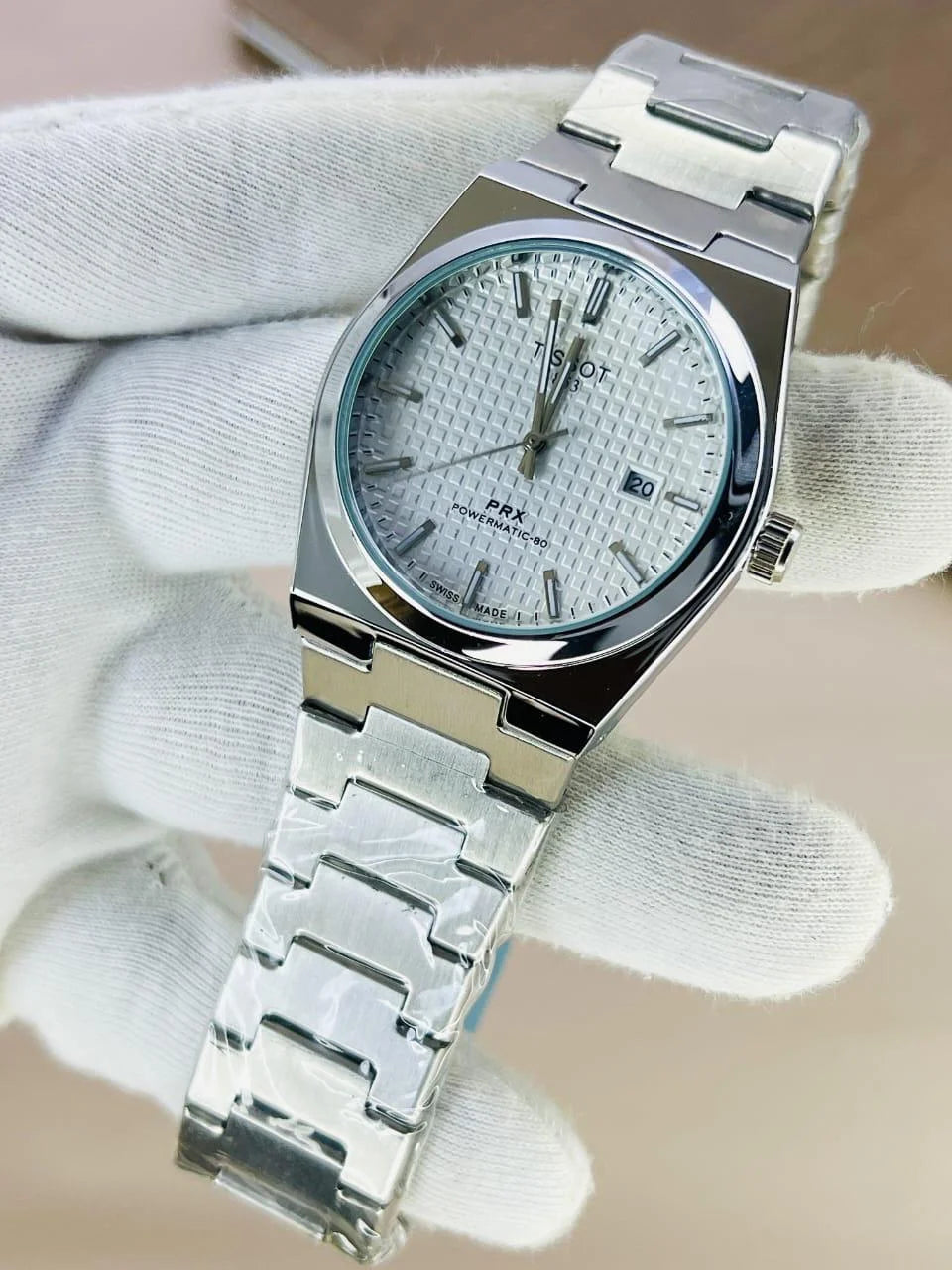 Tissot Prx Chain Watch in Silver White with stainless steel bracelet and textured dial held by gloved hand