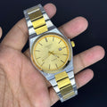 Tissot Prx Two Tone Watch In Gold with silver and gold stainless steel band held in hand