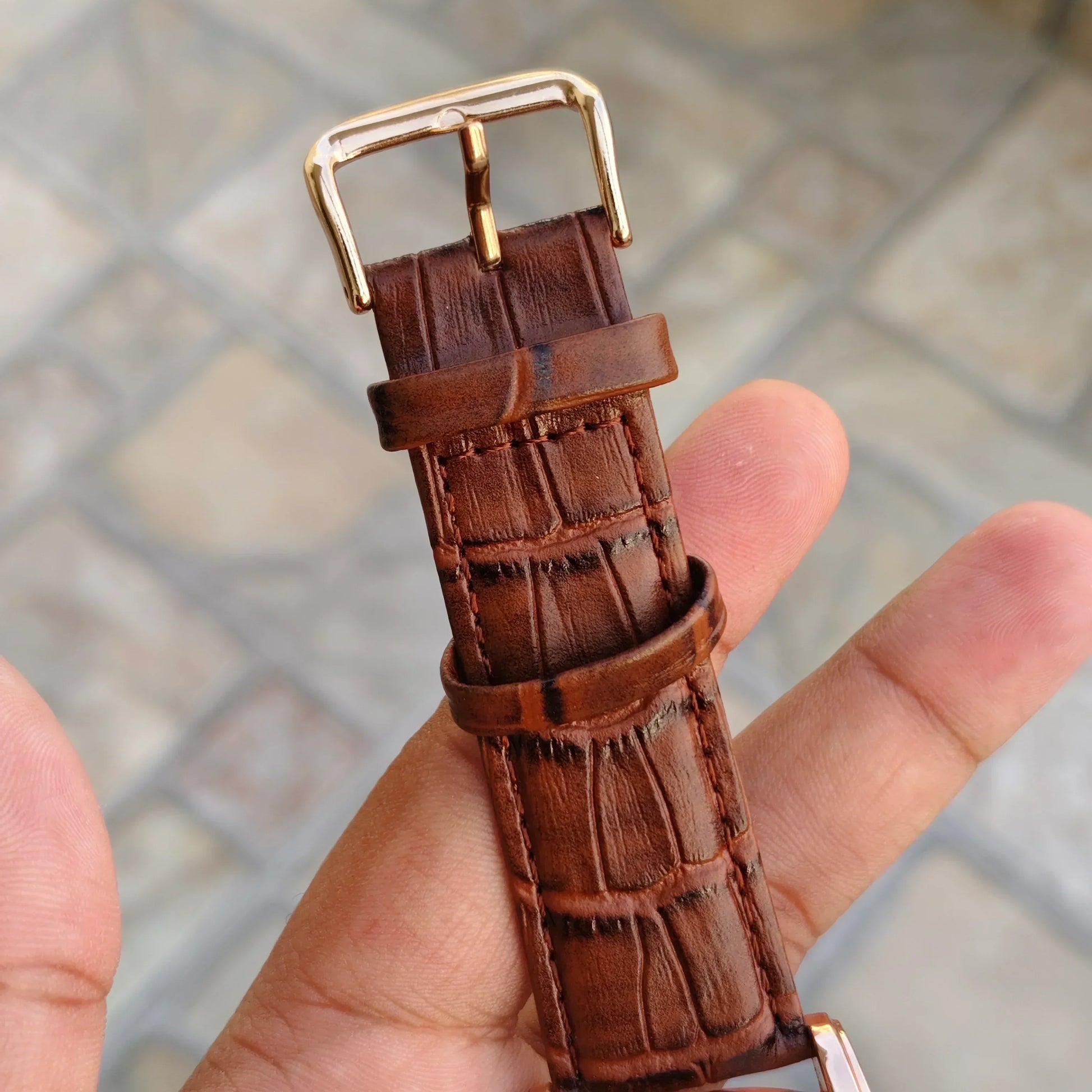 Close-up of brown textured leather strap with gold buckle of tomi t 103 dual strap watch for men