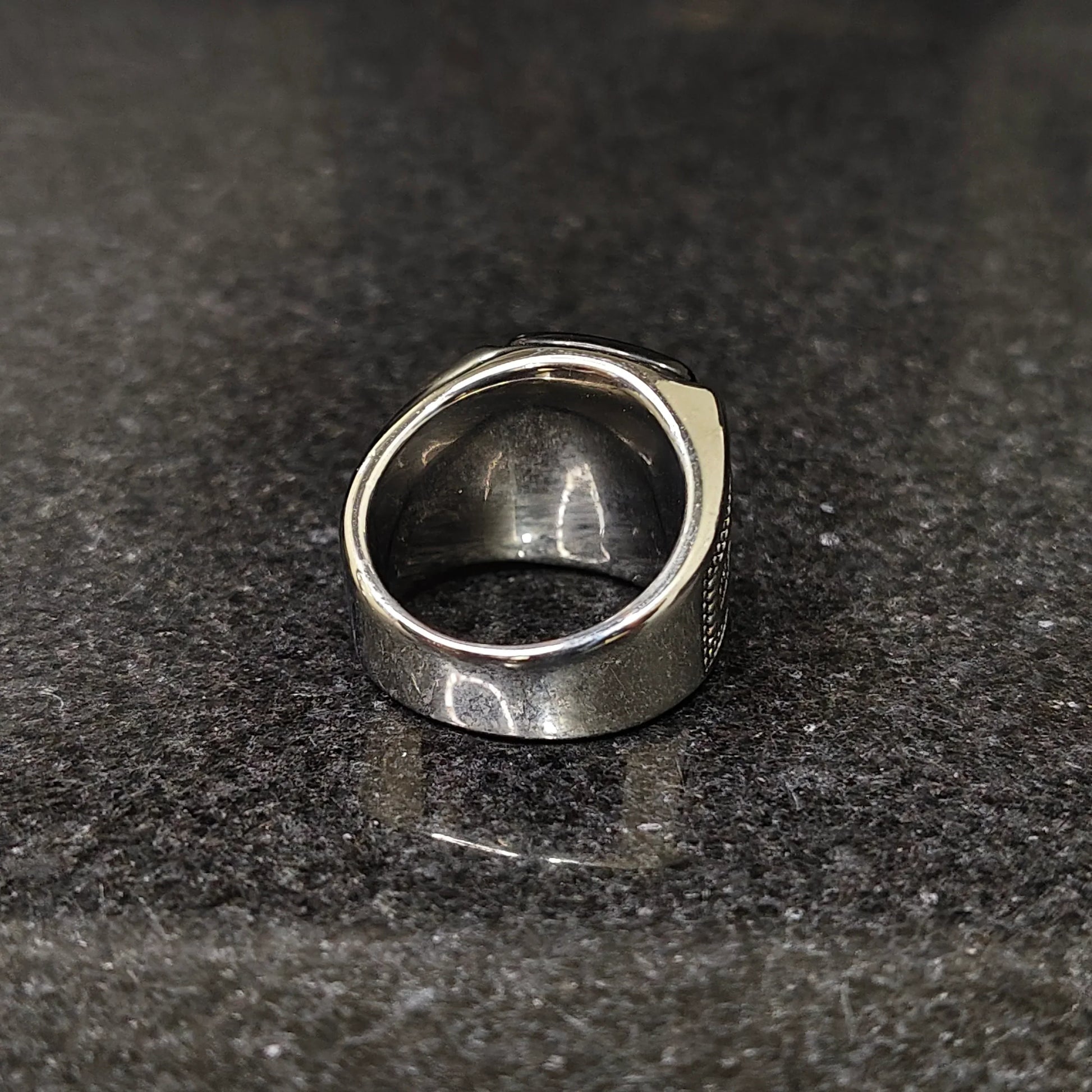 Silver Egyptian ring for men with detailed engravings on a dark stone surface
