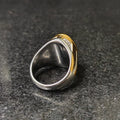 Silver gold oval medusa ring for men with mixed metal design on dark stone surface